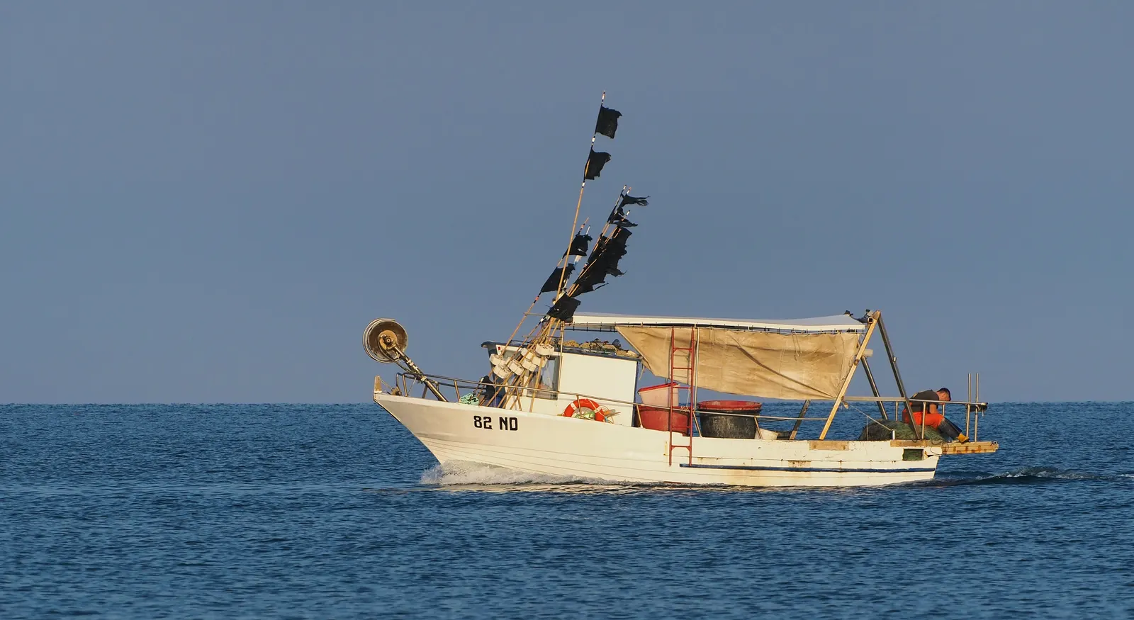 A small white fishing boat sails across the Adriatic Sea