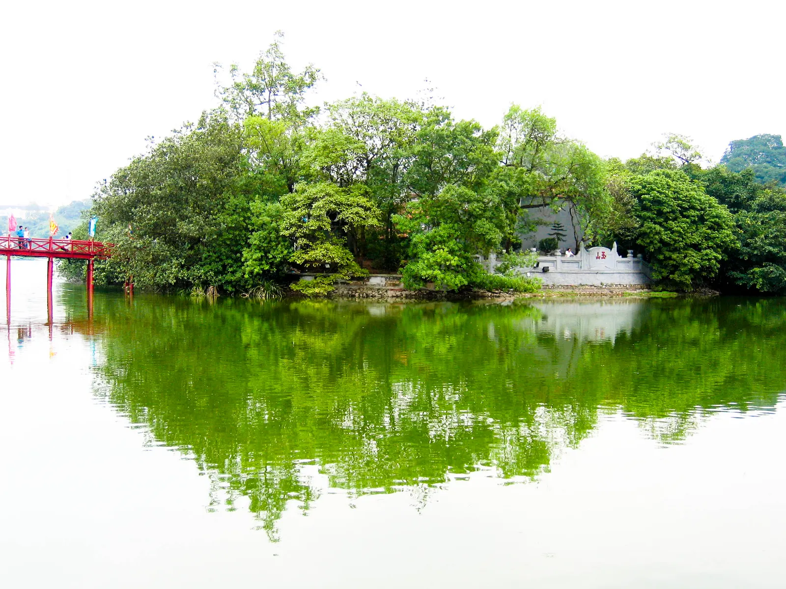 A red bridge and trees reflected in Hoan Kiem Lake in Hanoi.