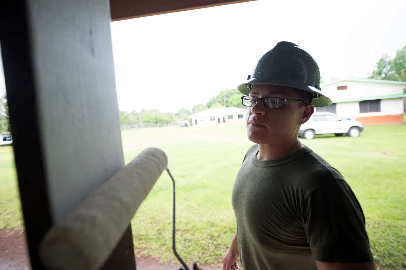 A worker repaints a window at Lukop Elementary School, with other school buildings in the background.