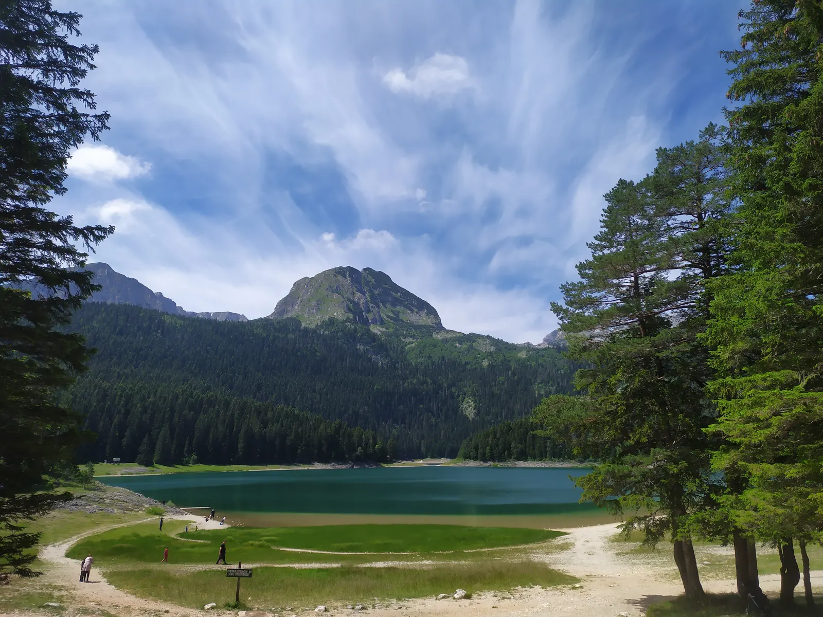 Crno Lake in Durmitor, surrounded by forest and mountains beneath a cloudy sky.