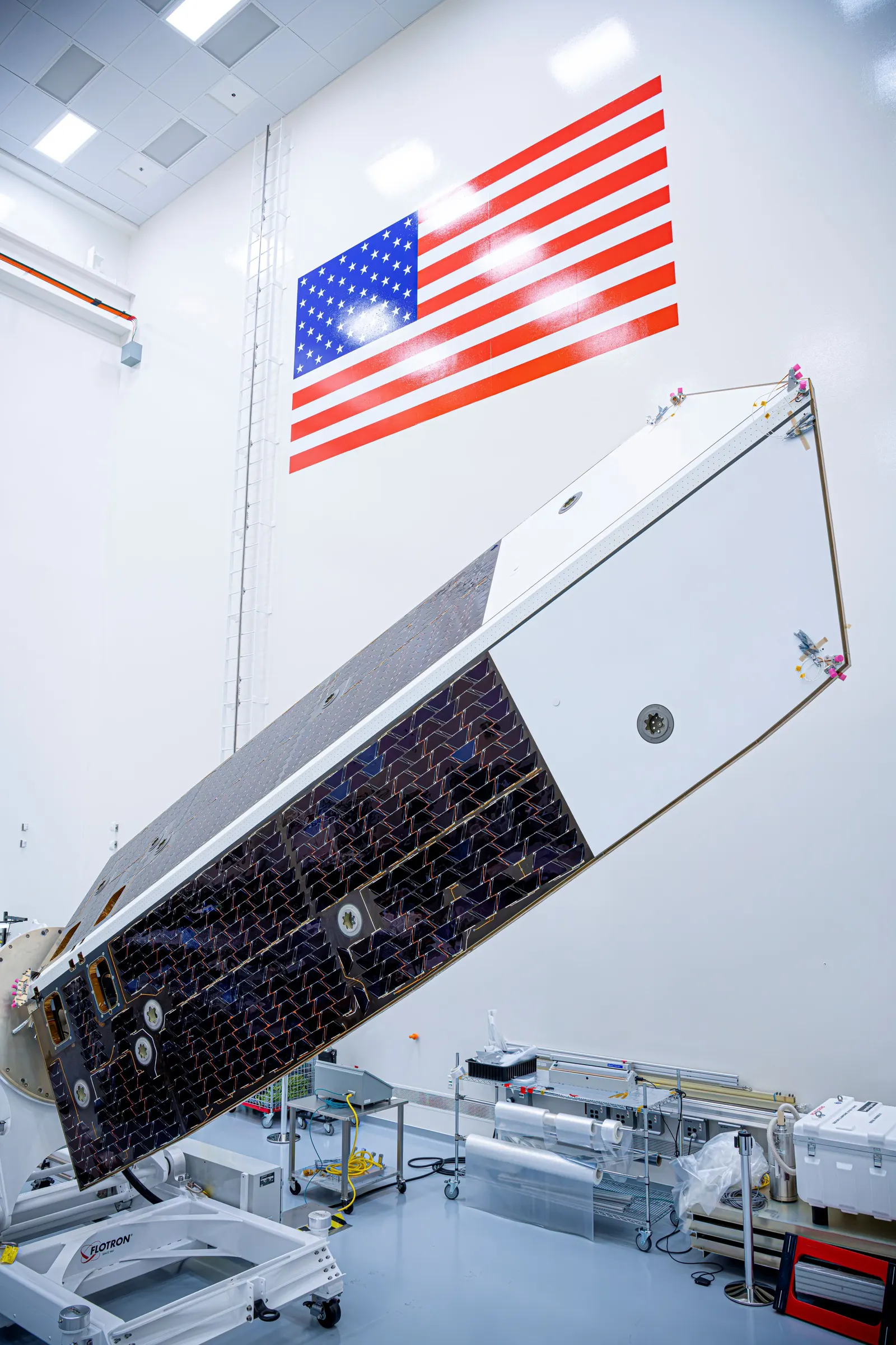 NEO Surveyor’s sunshade tilted on an assembly ring in a clean room, with dark solar cells and pale panels.