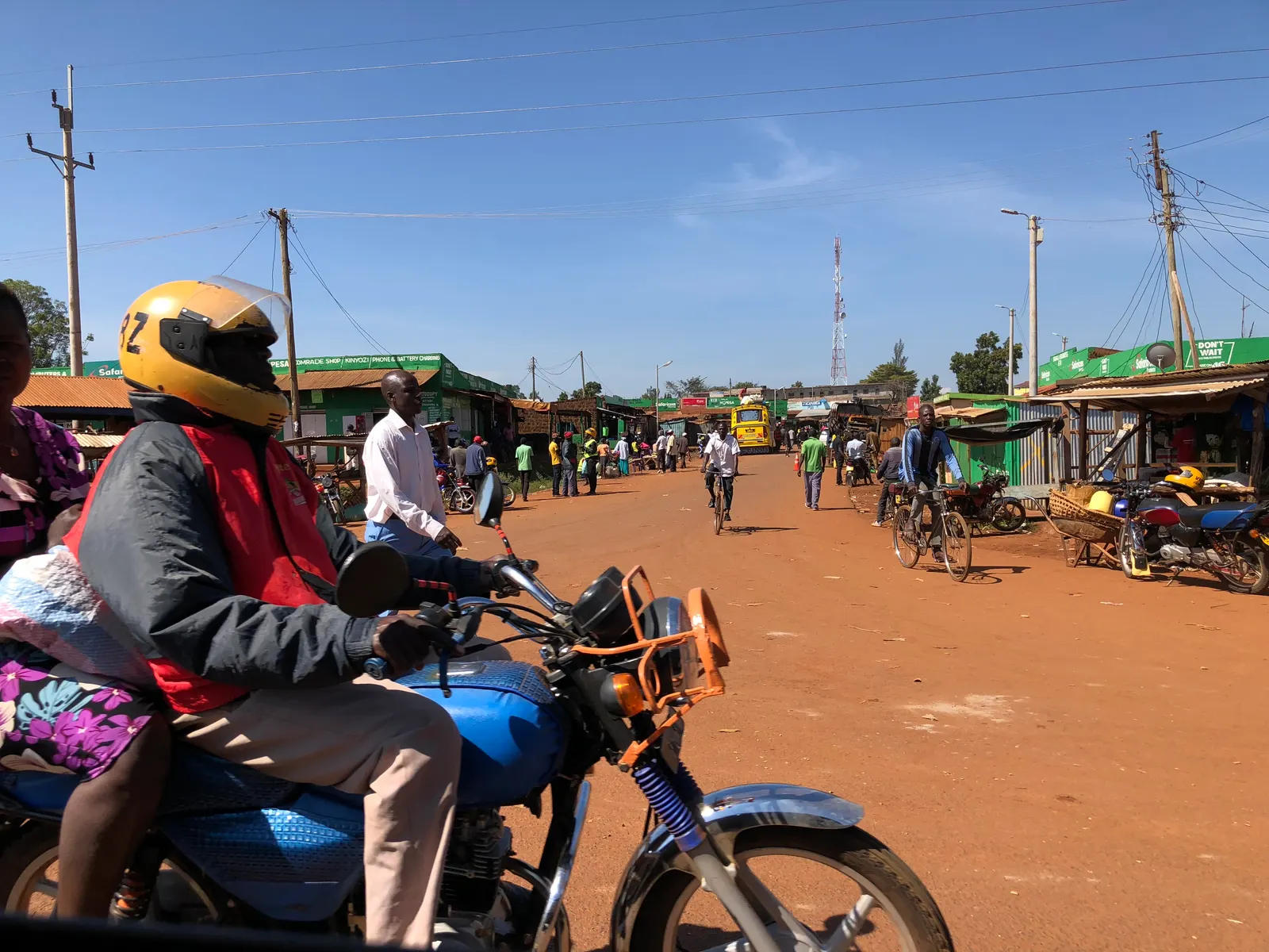 A street in Busia with motorcycles, pedestrians and shops.