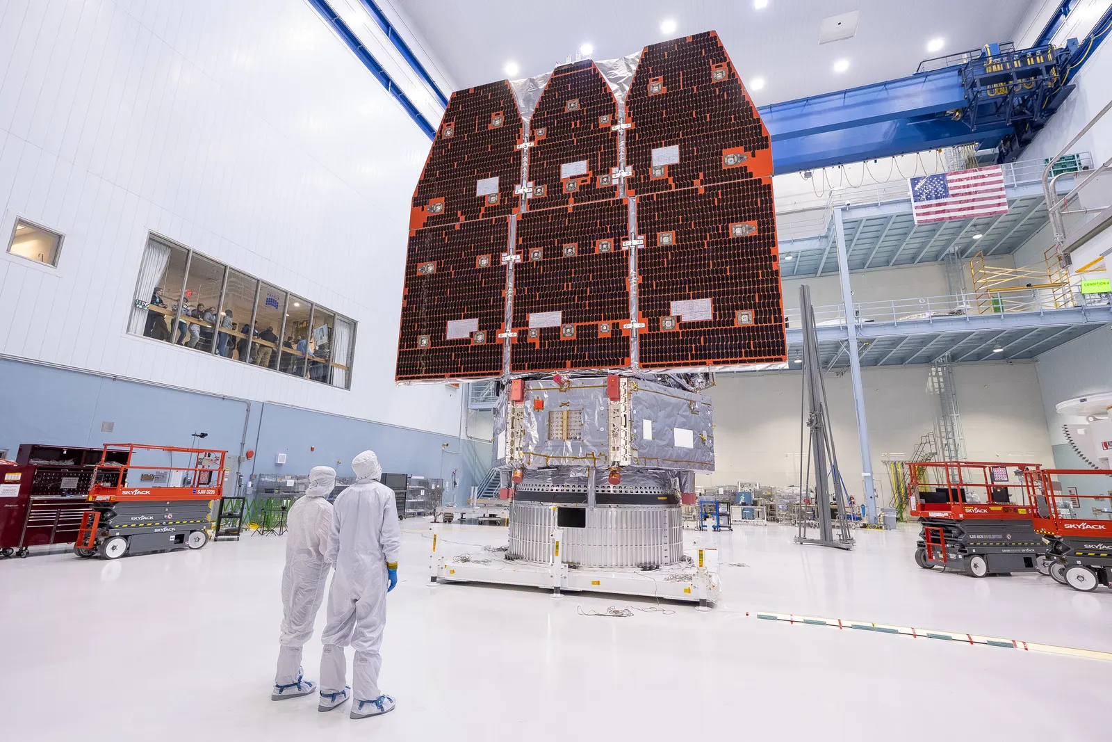 The assembled Roman Space Telescope in a cleanroom with two technicians wearing protective suits